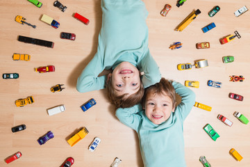 Adorable brothers lying on the ground with toy cars around