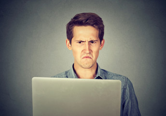 Frustrated disgusted man looking at laptop displeased with email