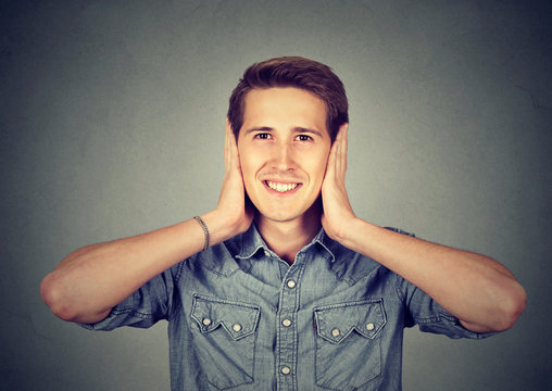 man covering his ears with hands. Hear no evil concept