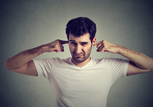 displeased man plugging ears with fingers doesn't want to listen