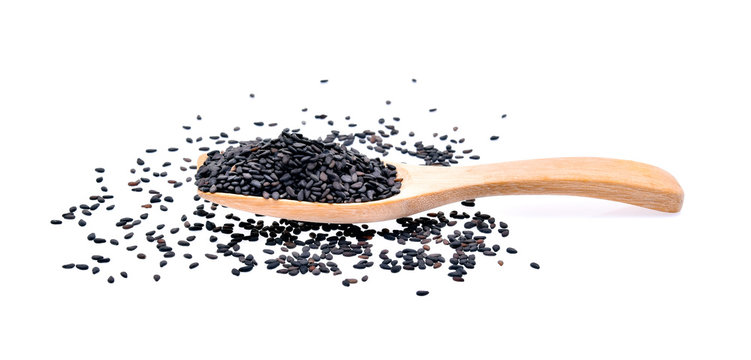 Black sesame seeds in a wooden spoon on white background