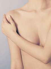 Bare woman covering her breast with hands