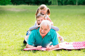 Portrait Of Grandfather And Grandchildren Lying On Grass