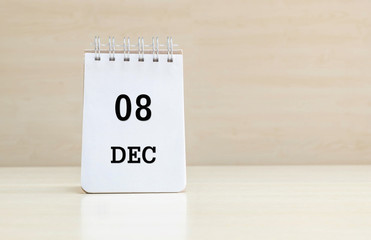 Closeup surface note book with purple 8 dec word in page on blurred brown wood desk and wood wall textured background with copy space under window light