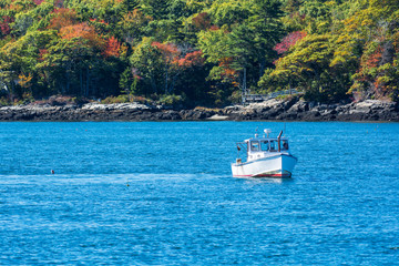 Fototapeta na wymiar Lobster fishing boat in autumn against deep blue ocean water in coastal Maine, New England