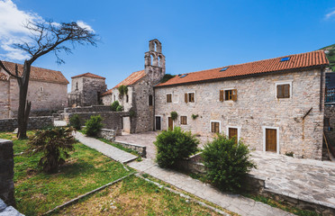 Fototapeta na wymiar Holy Trinity Church yard in Budva Old Town. Traditional stone church and houses in Montenegro.