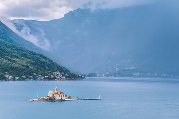 Catholic Church Of Our Lady Of The Rocks on Our Lady Of The Rocks island and Boka Kotorska landscape. One of the two islets near coast of Perast town at Kotor bay, Montenegro.
