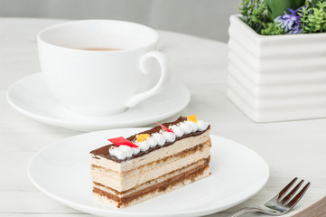 cake on a plate and a cup of coffee on a table with flowers