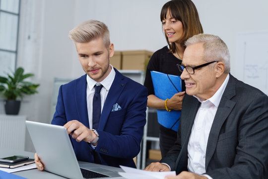 team im unternehmen schaut gemeinsam auf laptop