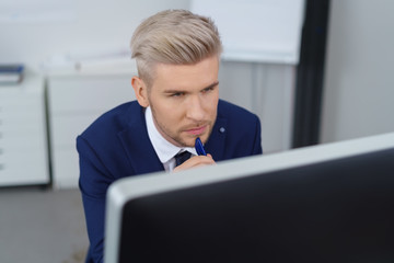 nachdenklicher mann im büro schaut aus seinen computer