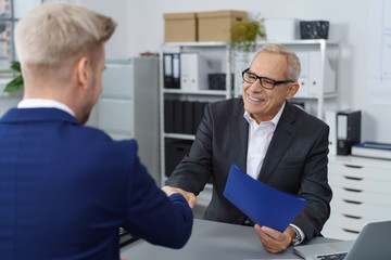 männer geben sich die hand beim bewerbungsgespräch