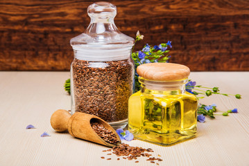 Linseed oil, flax seeds, and flowers on a light background.