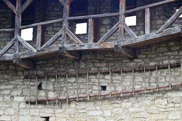 Fototapeta na wymiar Wooden balconies and stairs on the stone wall in an old fortress