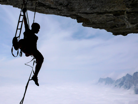 a climber aid climbing a large roof in the Swiss Alps near the Walensee