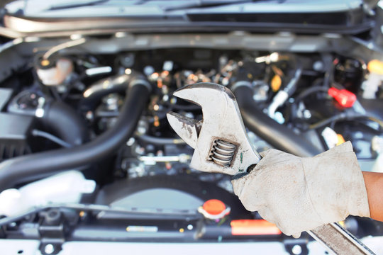 Hand with wrench checking car engine.