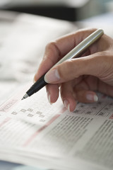 Woman making a crossword puzzle with a pen in her free time