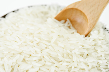 Raw white rice and wooden scoop in bowl.