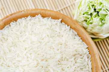 Raw white rice and wooden bowl.