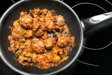 Meatballs with vegetables on a frying pan