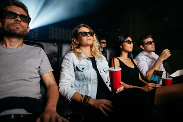 Young people with drinks watching 3d film