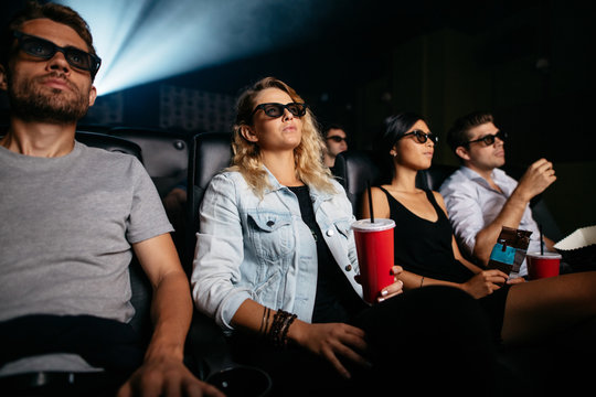 Young people with drinks watching 3d film