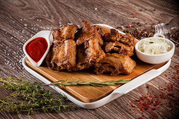 pork ribs grilled on a wooden board with a white plate, scattere