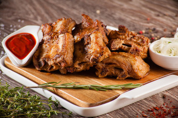 pork ribs grilled on a wooden board with a white plate, scattere