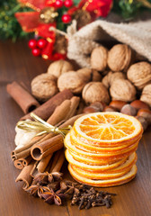 cinnamon sticks, nuts and dried orange slices, walnuts, pine tree on wooden background