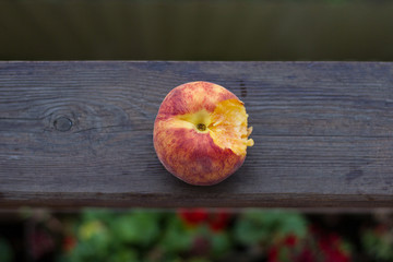 Sweet juicy appetizing bitten peach on a wooden background in nature.