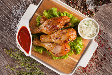 Chicken legs grilled on a wooden board with white cup and around