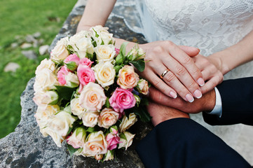 Hand on hand of wedding couple near wedding bouquet.