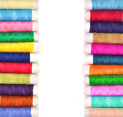 Pile of coloured bobbins of lurex thread isolated on white