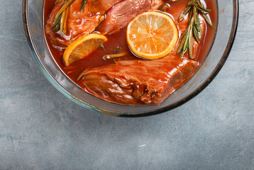 Beef fillet with lemon and rosemary in the glass bowl