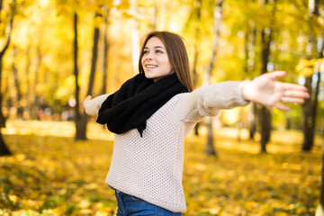 Exited young girl with rised hands in autumn park