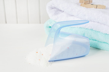 Bath towels, washing powder in measuring cup and wooden clothesp