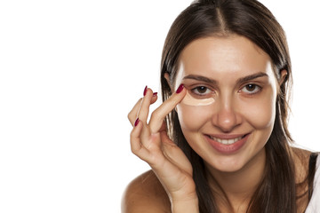 young women applied concealer under the eyes with her finger