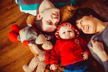 The parents with son lie on the carpet