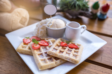 Strawberry waffle and honey with ice cream on wooden table, selective focus, lights effects.