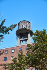 Fototapeta na wymiar Roof top water tank, with graffiti, made of wood on the top of a New York City apartment building with red brick facade