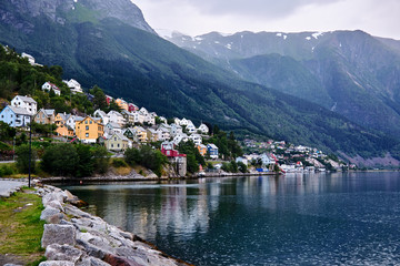 Fototapeta premium Colorful wood houses on a mountainside in Odda in Norway that leads to the inlet called Soerfjorden