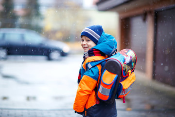 Happy kid boy having fun with snow on way to school