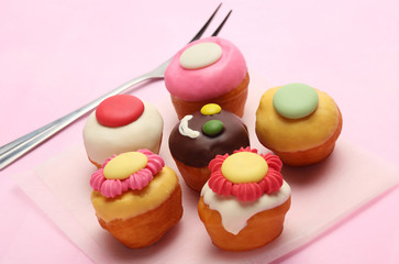 Small Cupcake Flower topping and Chocolate candy smile cupcake group and silver fork on sweet pink background