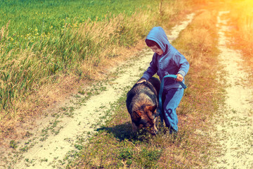 Happy little girl walking with dog on rural dirt road