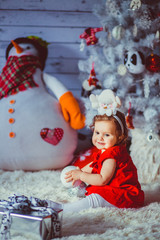 The small girl sits near christmas tree