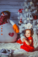 The small girl sits near christmas tree