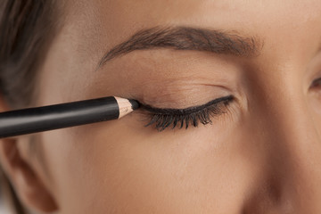 young woman applied eyeliner.