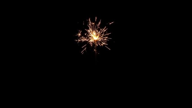 Centrally positioned firework sparkler burning from start to end in real time isolated. Full size uncropped expanded frame. Gun powder sparks shot against deep dark background.