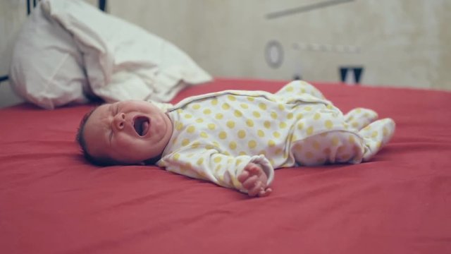 Baby lying on a bed crying
