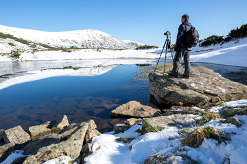 Photographer taking photos of beautiful landscape in the mountain lake. Winter lake. Travel inspiration and motivation, beautiful landscape.