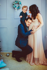 The father holds on shoulders his son and embraces  his wife